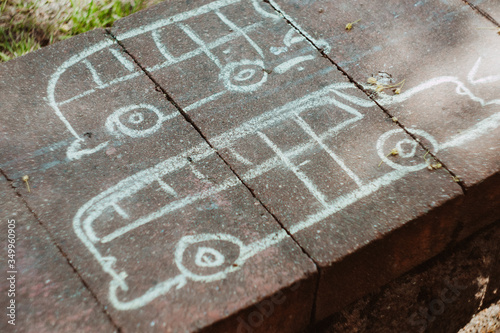 Chalked children's drawing of a car's on a paving.