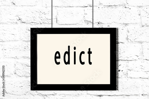 Φωτογραφία Black frame hanging on white brick wall with inscription edict