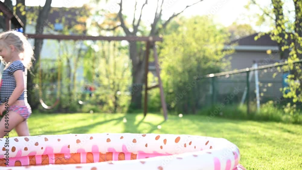 cute little girl playing with camera outside in backyard in springtime with inflatable pool cute little girl playing with camera outside in backyard in springtime with inflatable pool