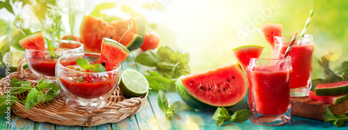 Summer refreshing watermelon drinks in glasses and cold soup gazpacho with basil on wooden table. Concept of healthy summer eating.