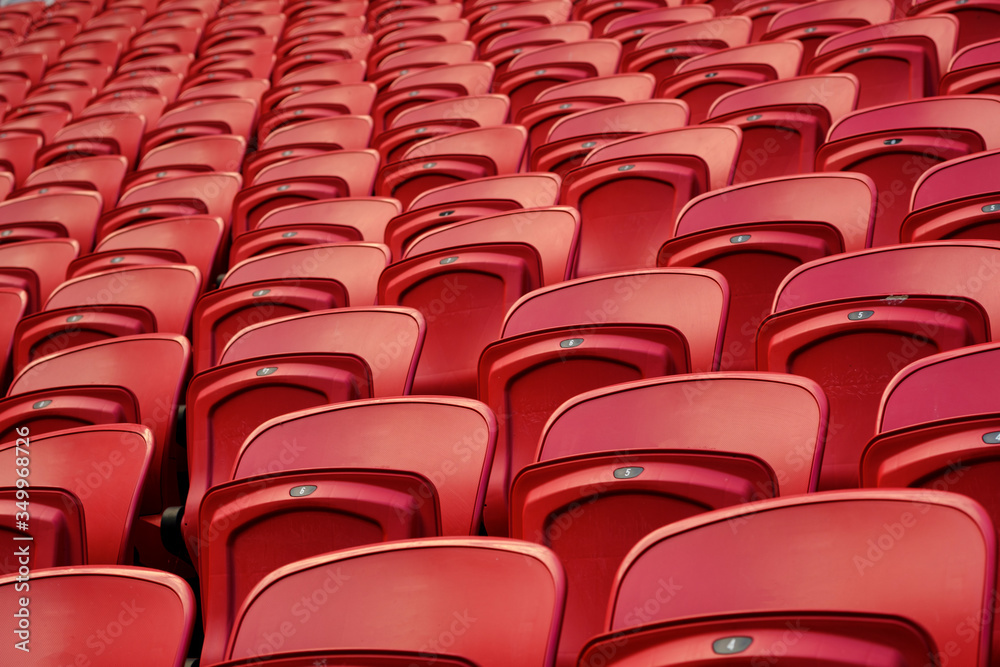 Fototapeta premium Empty red plastic seats in an empty stadium. Many empty seats for spectators in the stands. Empty plastic chairs seats for football fans.
