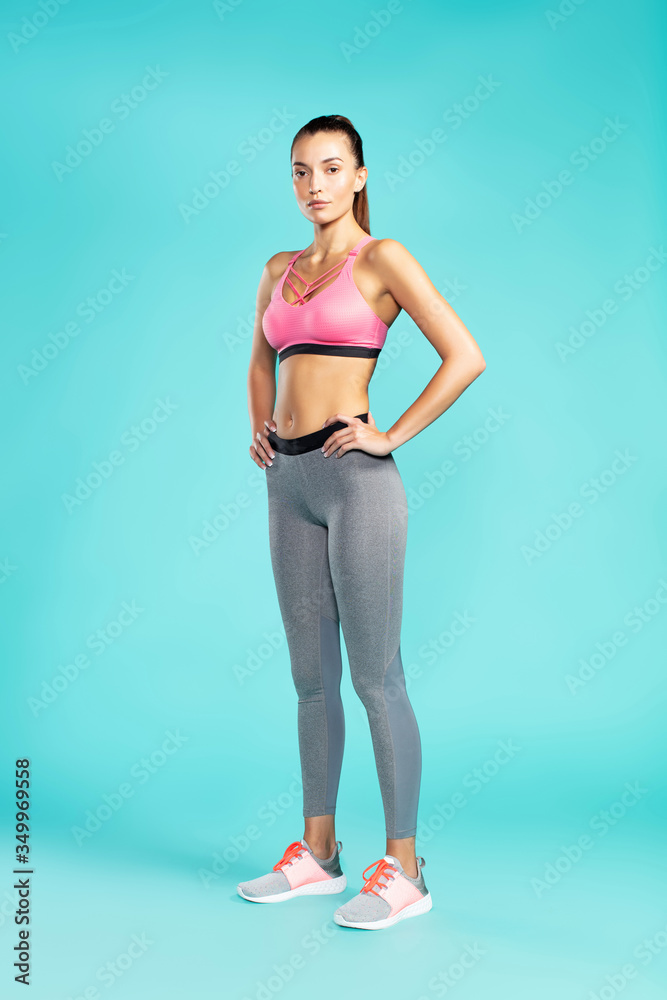 Ready for workout. Full length of young beautiful woman in sportswear looking at camera while standing against blue background. Sport and fitness Ready for workout. Full length of young beautiful woman in sportswear looking at camera while standing against blue background. Sport and fitness