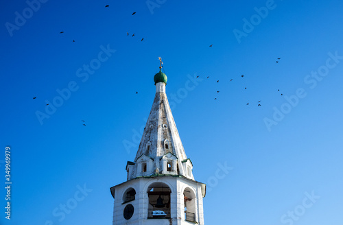 Birds circle the bell tower of the Orthodox ascension Church in Suzdal in winter.