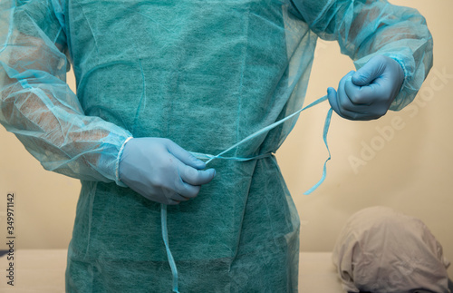 Physiotherapist wears disposable gown. Preparation for rehabilitation therapy with personal protective equipment. Medicine and health in coronavirus times (covid-19) photo