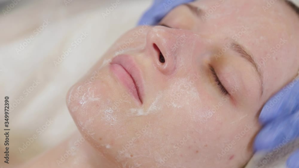 Professional beautician washes a woman and massages her face.