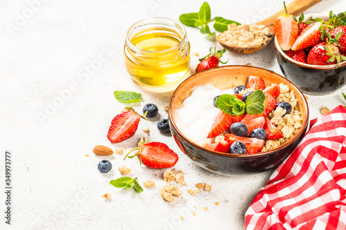 Greek yogurt granola with fresh berries on white stone table.
