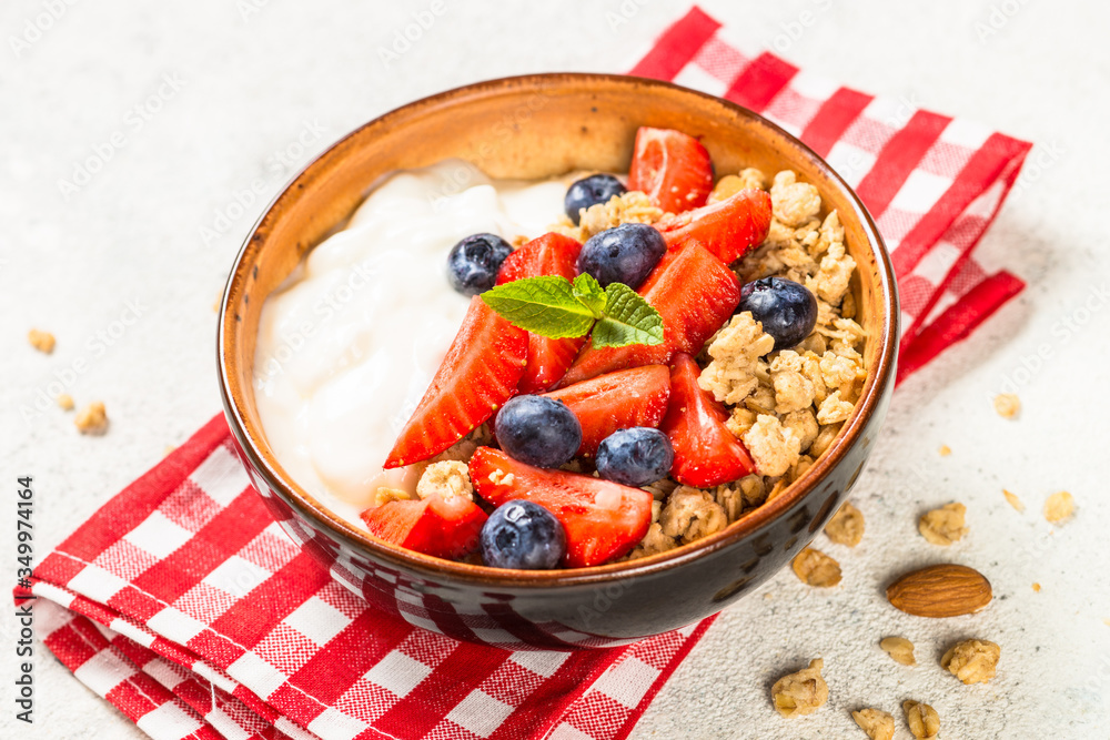 Greek yogurt granola with fresh berries on white stone table.