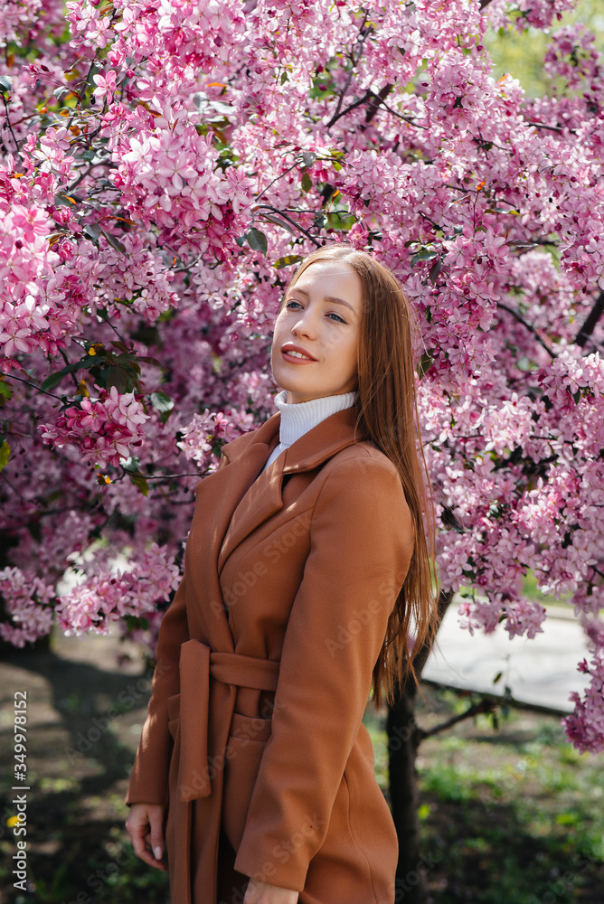 A beautiful young girl walks on a spring day in a blooming Apple orchard. Lifestyle, recreation A beautiful young girl walks on a spring day in a blooming Apple orchard. Lifestyle, recreation