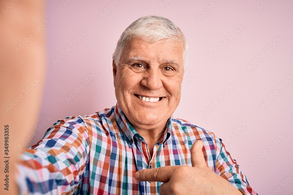 Senior handsome hoary man wearing casual shirt making selfie by the camera with surprise face pointing finger to himself Senior handsome hoary man wearing casual shirt making selfie by the camera with surprise face pointing finger to himself