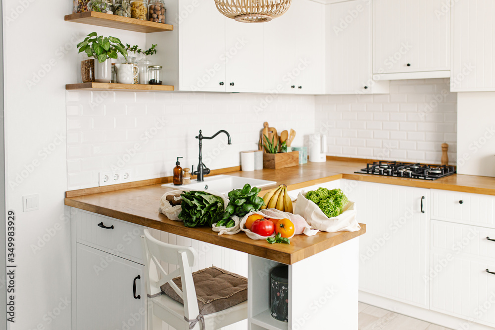 Fresh vegetables and fruits in eco cotton bags on table in the kitchen.