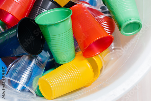 A large pile of multicolored plastic cups scattered on the floor. Pollution of the environment by human waste