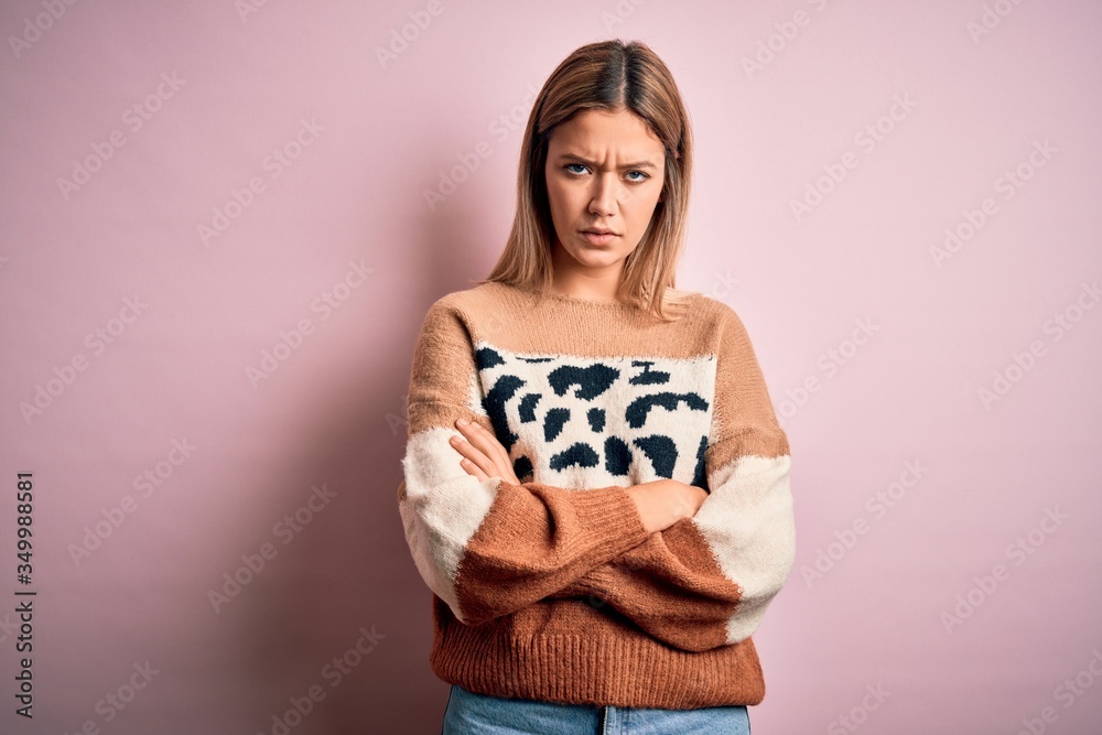 Young beautiful blonde woman wearing fashion animal print sweater over pink background skeptic and nervous, disapproving expression on face with crossed arms. Negative person. Young beautiful blonde woman wearing fashion animal print sweater over pink background skeptic and nervous, disapproving expression on face with crossed arms. Negative person.
