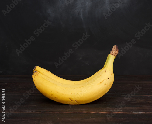 bunch of yellow unpeeled ripe bananas on a brown wooden table