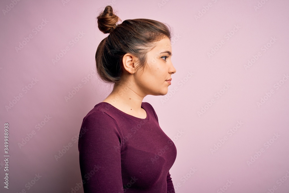 Beautiful young woman wearing casual bun hairstyle over pink isolated background looking to side, relax profile pose with natural face with confident smile. Beautiful young woman wearing casual bun hairstyle over pink isolated background looking to side, relax profile pose with natural face with confident smile.