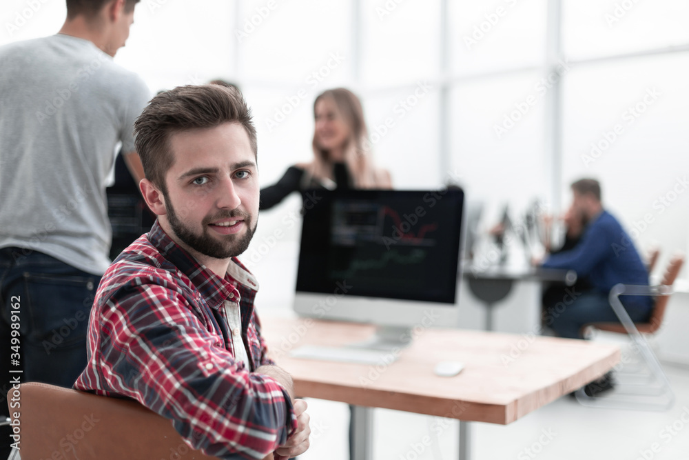 young employee sitting at the office Desk and looking at the camera. young employee sitting at the office Desk and looking at the camera.