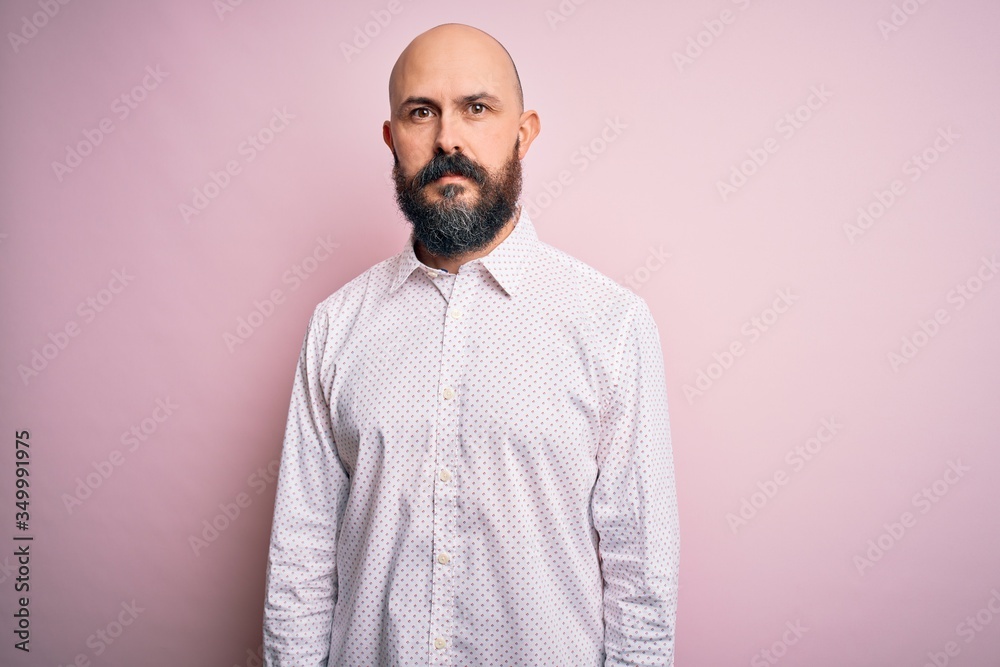 Handsome bald man with beard wearing elegant shirt over isolated pink background Relaxed with serious expression on face. Simple and natural looking at the camera.