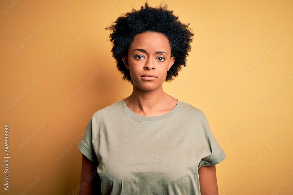 Young beautiful African American afro woman with curly hair wearing casual t-shirt Relaxed with serious expression on face. Simple and natural looking at the camera. Young beautiful African American afro woman with curly hair wearing casual t-shirt Relaxed with serious expression on face. Simple and natural looking at the camera.