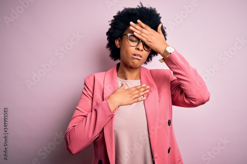 Young beautiful African American afro businesswoman with curly hair wearing pink jacket Touching forehead for illness and fever, flu and cold, virus sick © Krakenimages.com