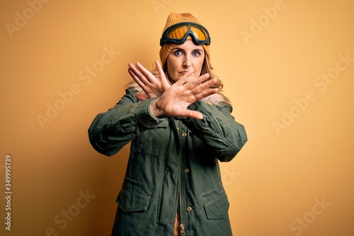 Middle age beautiful blonde skier woman wearing snow sportwear and ski goggles Rejection expression crossing arms doing negative sign, angry face © Krakenimages.com