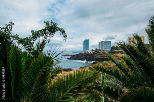 Tropical island of Tenerife. The coast of a Spanish city on the Atlantic ocean. Panorama of the city and beach on the island of Tenerife. Background color with gradient and grain, sound effect. © Евгений Симдянкин