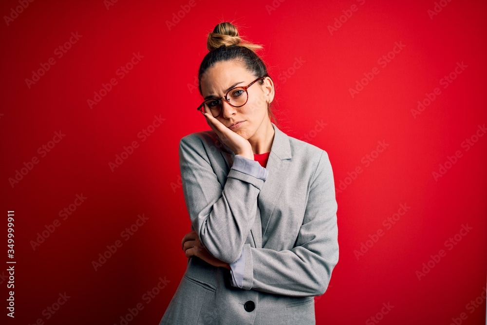 Young beautiful blonde businesswoman with blue eyes wearing glasses and jacket thinking looking tired and bored with depression problems with crossed arms.