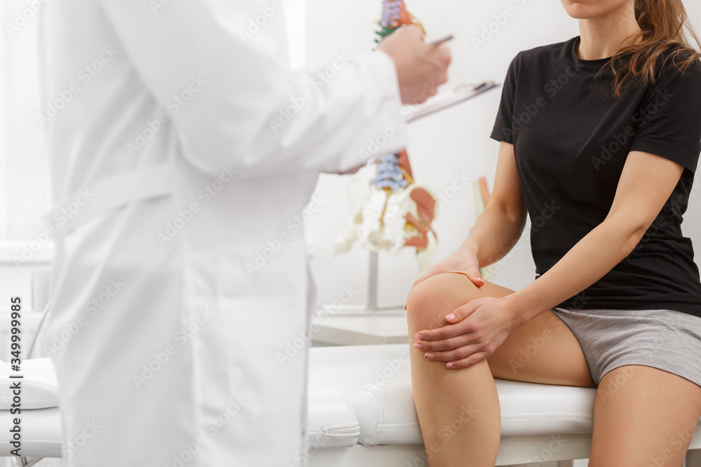 Φωτογραφία Male doctor examining female patient suffering from knee pain