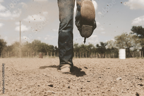 Cowboy boots in dirt arena kicking up dirt on summer day, western lifestyle. photo