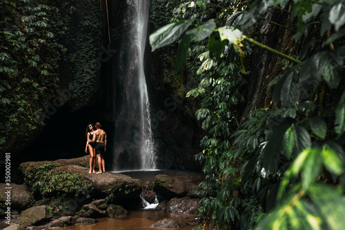 Lovers at the waterfall. Couple admiring a beautiful waterfall in Indonesia. Couple on vacation in Bali. Honeymoon trip. The couple is traveling in Asia. Vacation on the island of Bali