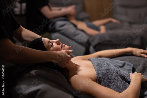 two attractive caucasian ladies enjoy spa procedures, young girls get anti aging face lifting by professional masseurs. spa therapy, skin treatment