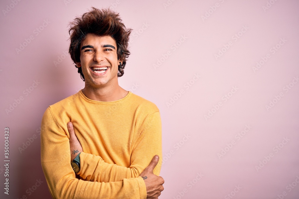 Young handsome man wearing yellow casual t-shirt standing over isolated pink background happy face smiling with crossed arms looking at the camera. Positive person. Young handsome man wearing yellow casual t-shirt standing over isolated pink background happy face smiling with crossed arms looking at the camera. Positive person.