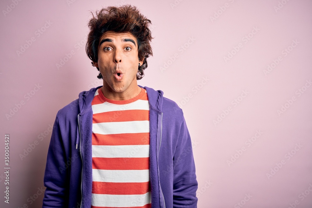 Young man wearing striped t-shirt and purple sweashirt over isolated pink background afraid and shocked with surprise expression, fear and excited face.