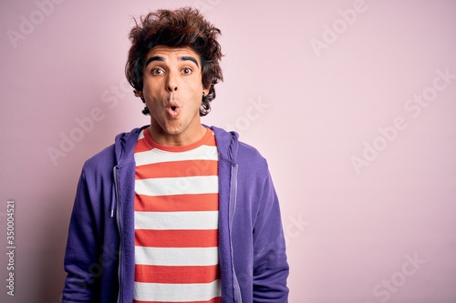 Young man wearing striped t-shirt and purple sweashirt over isolated pink background afraid and shocked with surprise expression, fear and excited face. © Krakenimages.com