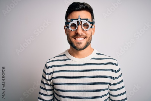 Young handsome man with beard wearing optometry glasses over isolated white background with a happy and cool smile on face. Lucky person.