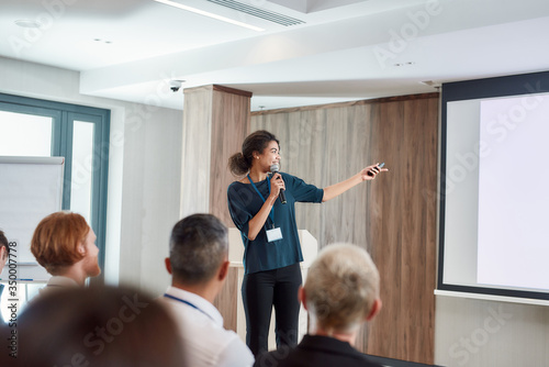 Dependable, professional partnership. Female speaker with laser pointer pointing at the screen while giving a talk on corporate business meeting