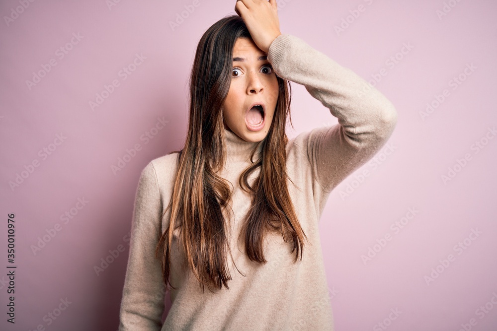 Young beautiful girl wearing casual turtleneck sweater standing over isolated pink background surprised with hand on head for mistake, remember error. Forgot, bad memory concept. Young beautiful girl wearing casual turtleneck sweater standing over isolated pink background surprised with hand on head for mistake, remember error. Forgot, bad memory concept.