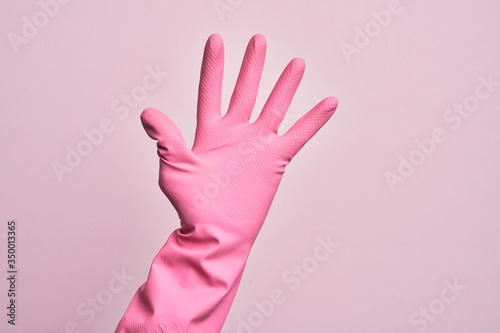 Hand of caucasian young man with cleaning glove over isolated pink background counting number 5 showing five fingers