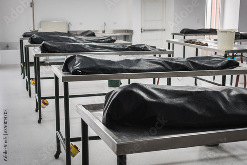 Φωτογραφία Covered human corpses on tables in a morgue / mortuary waiting for identification, autopsy, burial or cremation