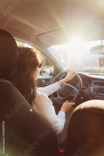 Fotografiet Young beautiful woman driving a car on road in the sunlight.