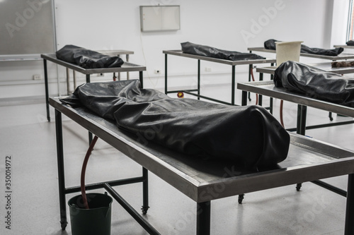 Covered human corpses on tables in a morgue / mortuary waiting for identification, autopsy, burial or cremation. Taken in Armenia, Colombia.