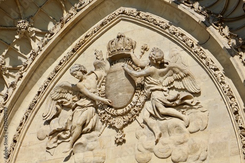 Pediment of Sainte Croix Cathedral in Orléans City (France) shot slightly from underneath during daytime with a gothic arch depicting two angels surrounding a coat of arms headed by a crown