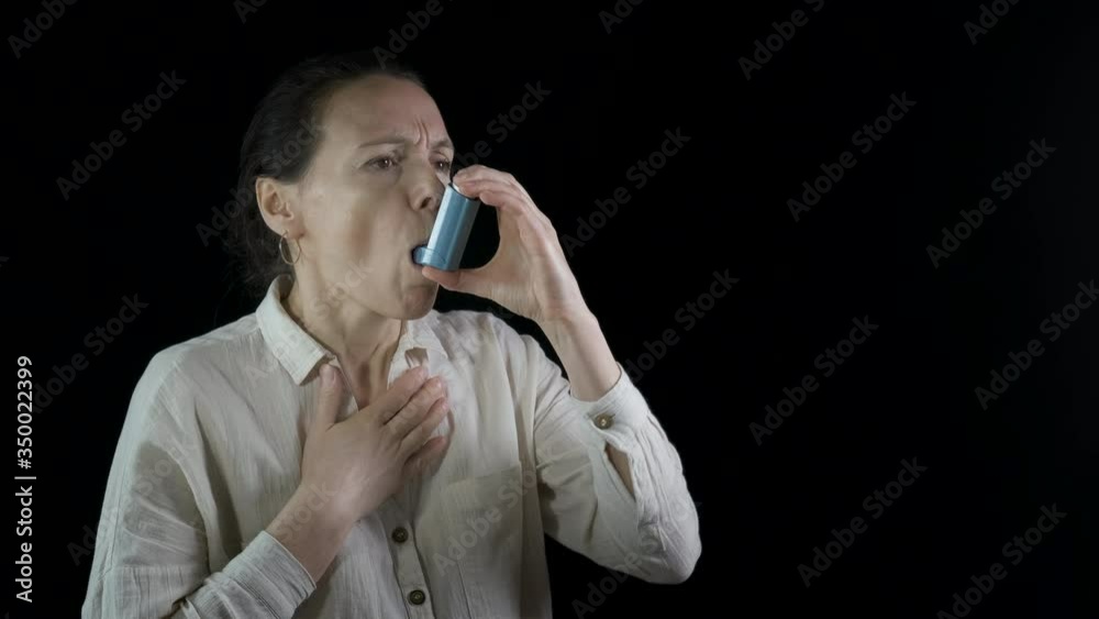 Woman with hard asthma. A choking woman uses an inhaler. Asthmatic attack.
