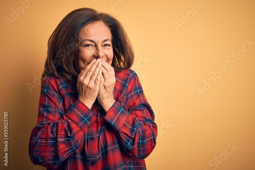 Принти на полотні Middle age beautiful woman wearing casual shirt standing over isolated yellow ba