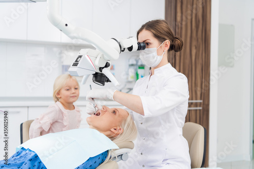 A female dentist examines the oral cavity of her patient on the dentist s chair