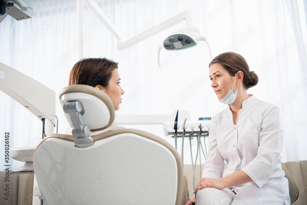 A closeup portrait of a female dentist consulting her patient. P