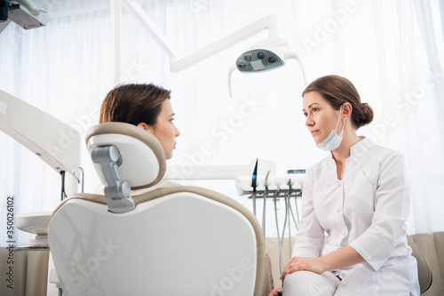 A closeup portrait of a female dentist consulting her patient. P