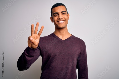 Young handsome african american man wearing casual sweater over white background showing and pointing up with fingers number three while smiling confident and happy. © Krakenimages.com