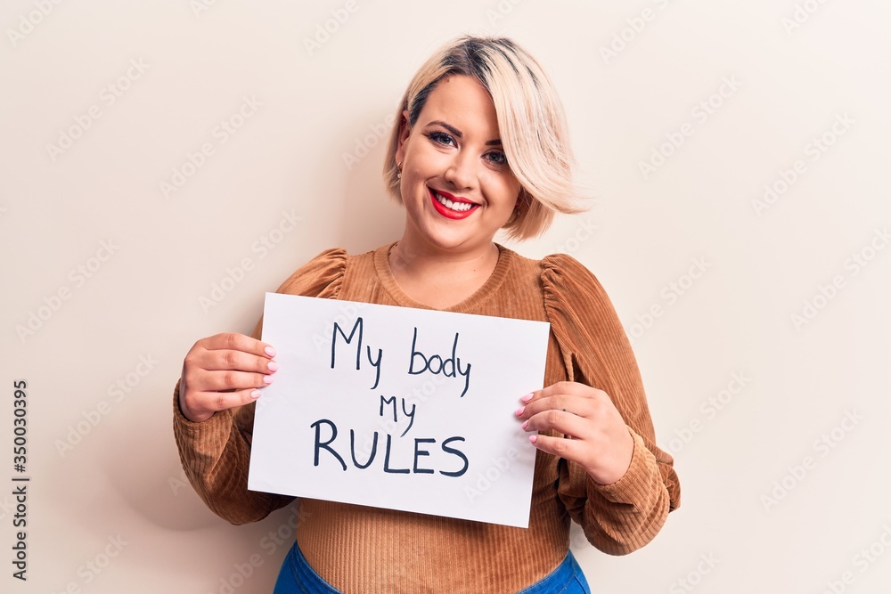 Blonde plus size woman asking for women rights holding paper with my body my rules message looking positive and happy standing and smiling with a confident smile showing teeth Blonde plus size woman asking for women rights holding paper with my body my rules message looking positive and happy standing and smiling with a confident smile showing teeth
