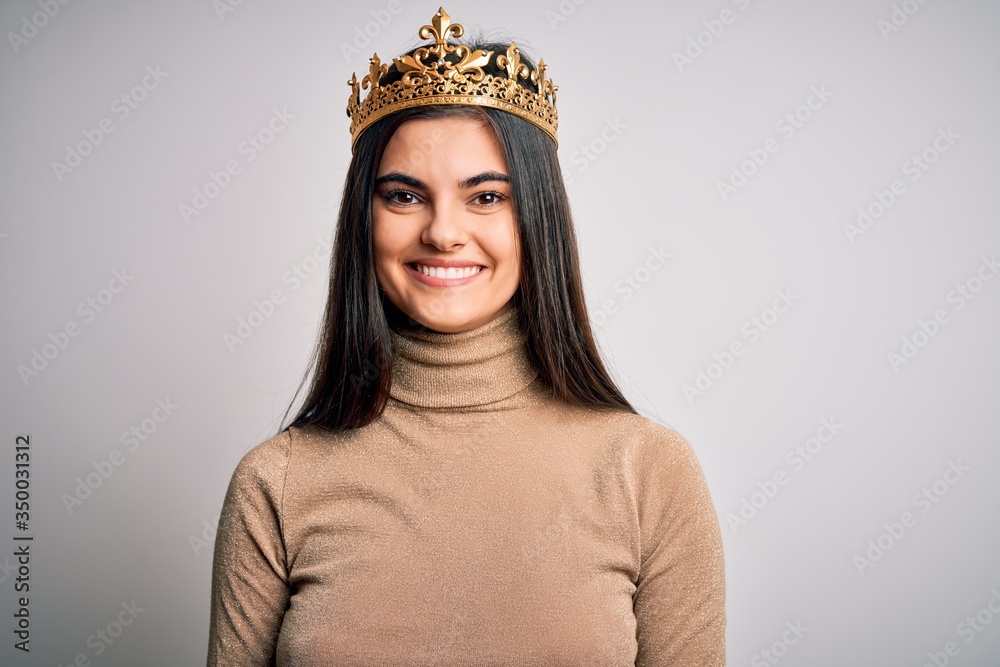 Φωτογραφία Young beautiful brunette woman wearing golden queen crown over isolated white background with a happy and cool smile on face