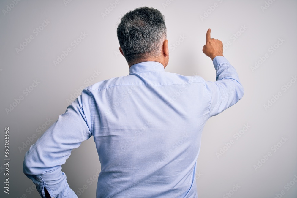 Middle age handsome grey-haired business man wearing elegant shirt and tie Posing backwards pointing ahead with finger hand Middle age handsome grey-haired business man wearing elegant shirt and tie Posing backwards pointing ahead with finger hand