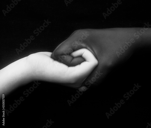 Monochromatic photo for two hands different in colors / black and white, showing unity, harmony, integration, and acceptance fighting against racism,prejudice, discrimination, racialism and xenophobia
